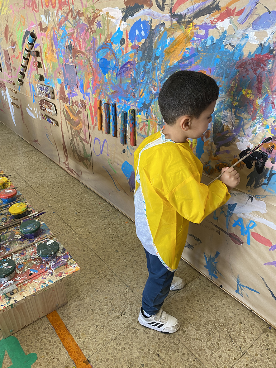 Imatge d'un alumne pintant el mural del pati