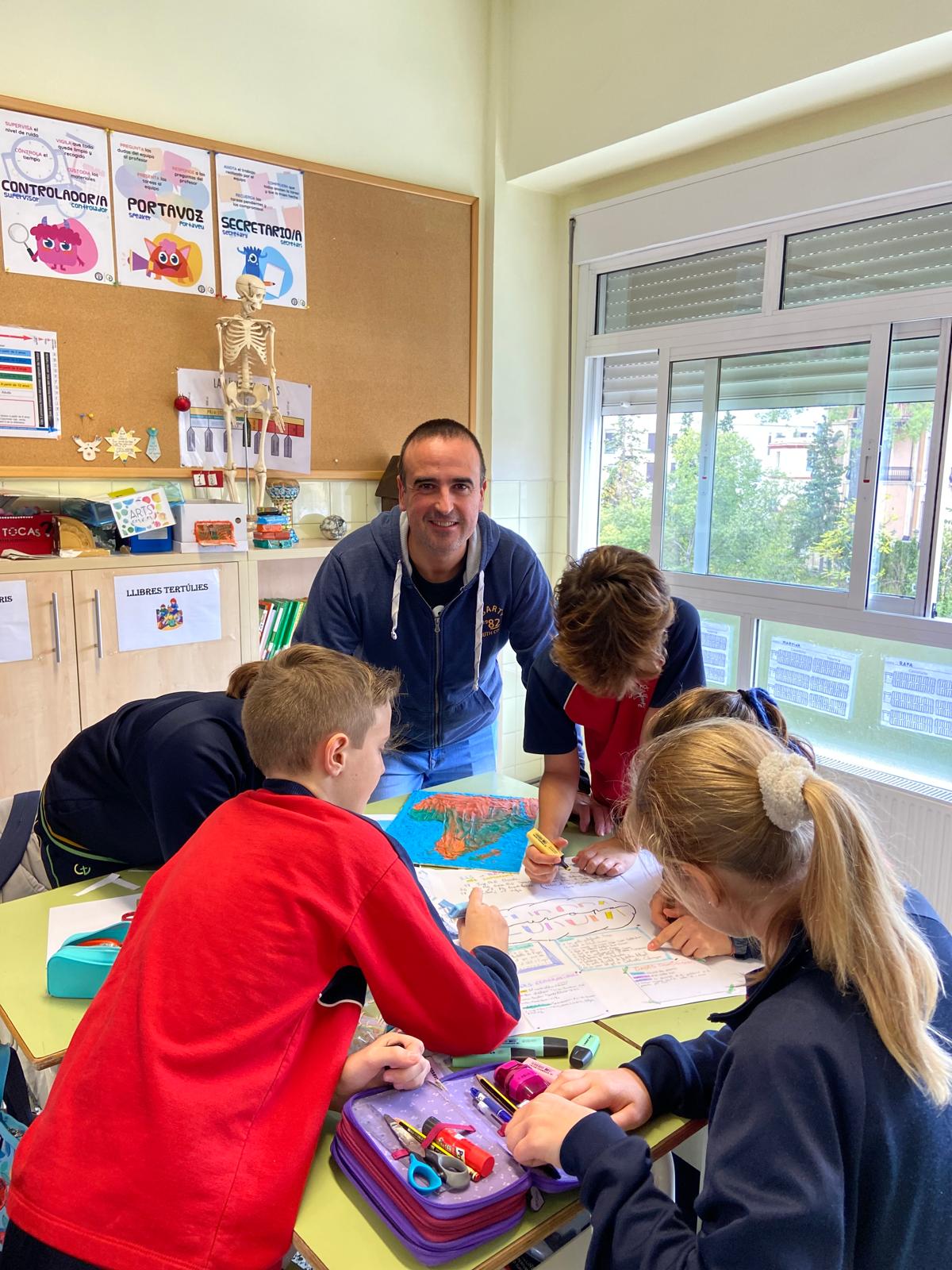 Diferentes alumnos junto con el docente realizando una actividad alrededor de una mesa