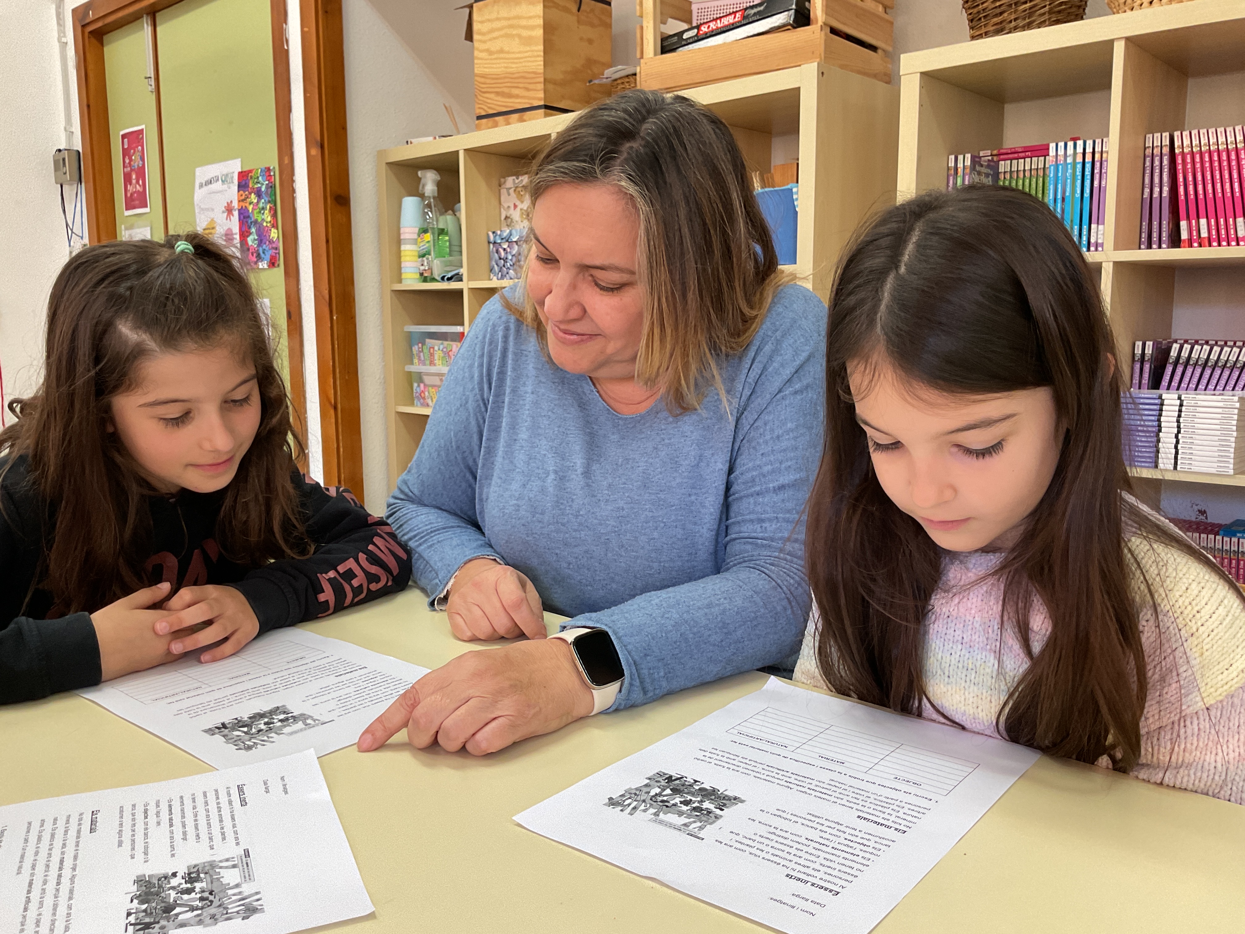 Una docente con dos alumnas mirando las actividades a realizar