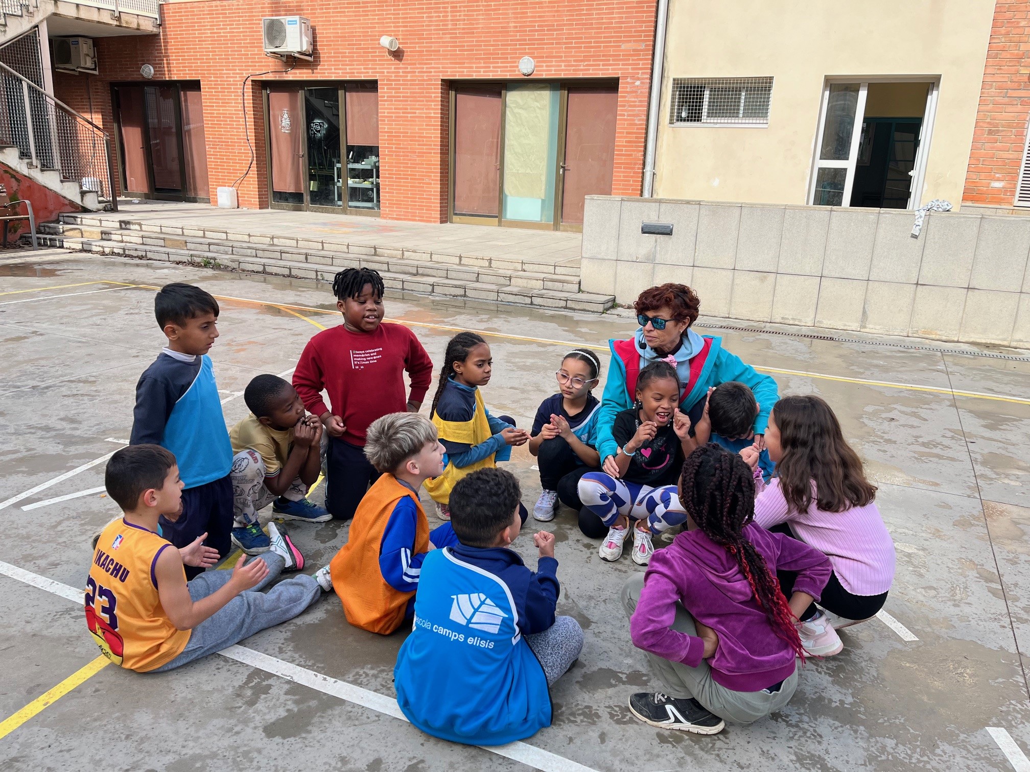 Un grupo de alumnos y la maestra en circulo hablando en el patio