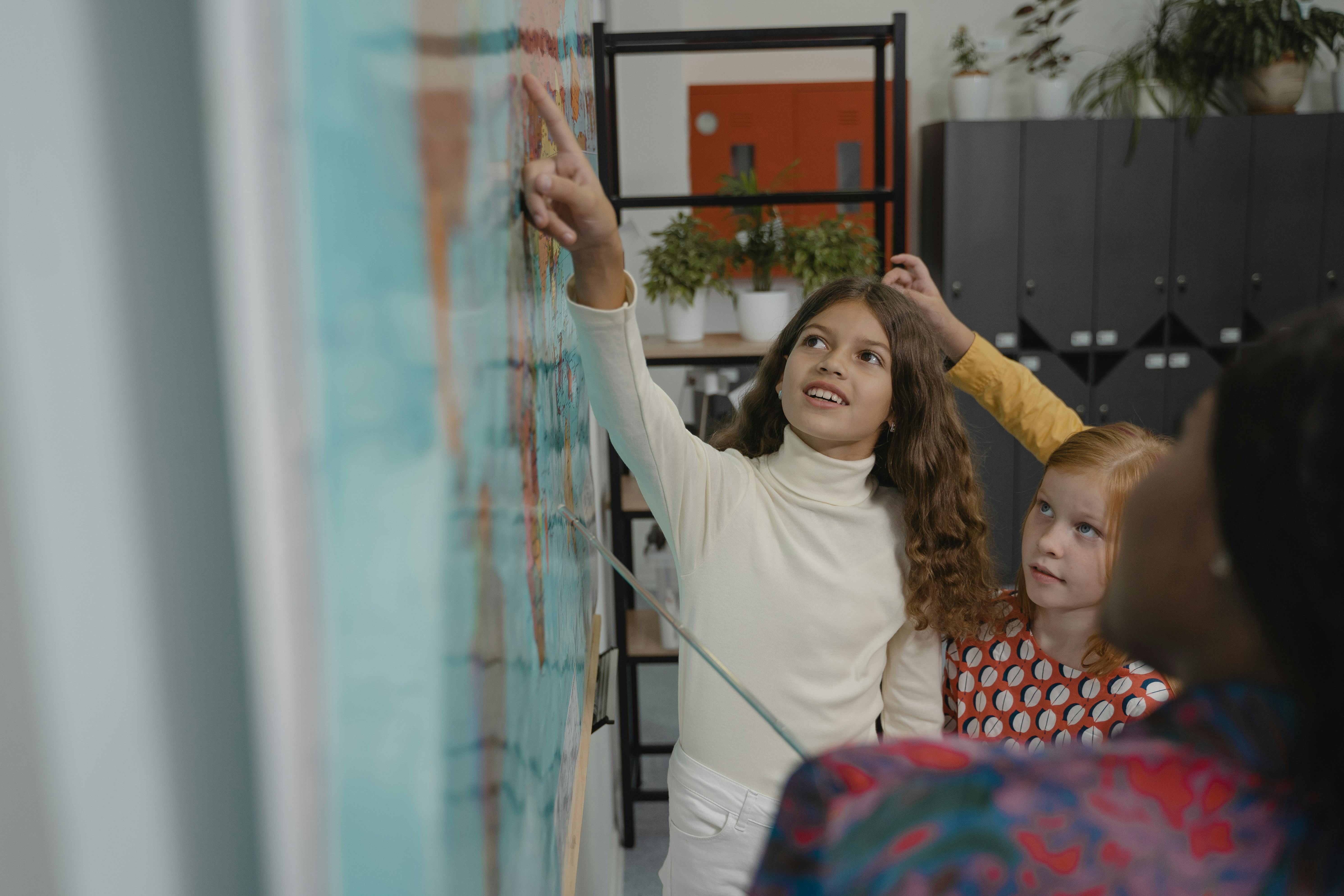 Dos alumnas señalando un mapa que cuelga en la pizarra de la clase